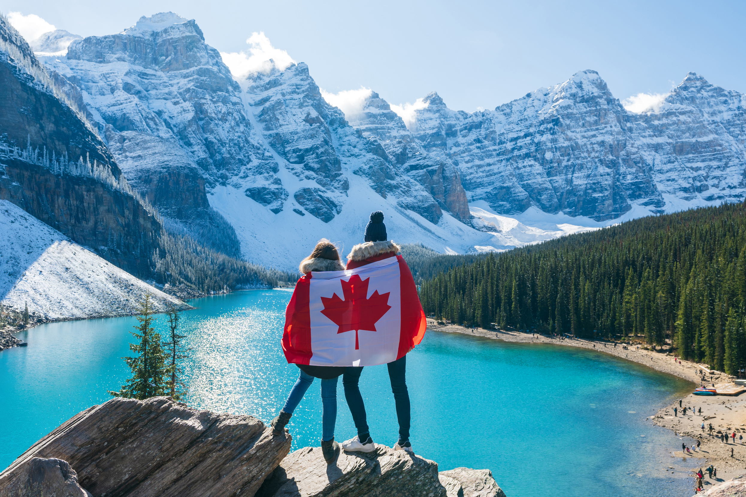 People draped in Canadian flag looking beautiful scenery of Moraine lake.